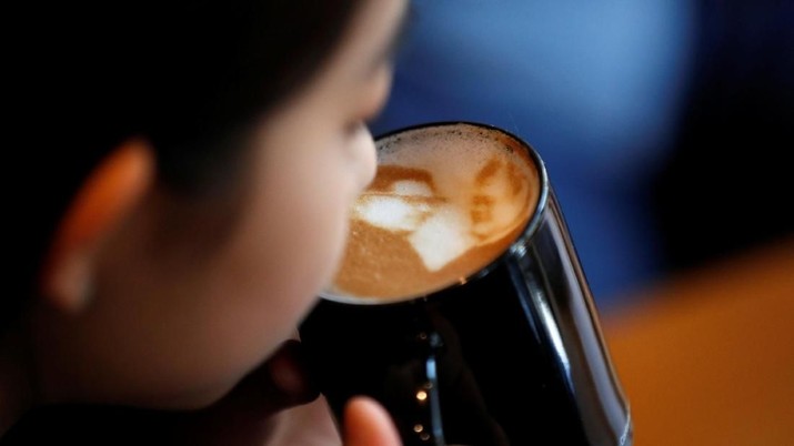 A woman drinks a latte with a picture of North Korean leader Kim Jong Un and South Korean President Moon Jae-in printed on the top of milk foam at a coffee shop in Jeonju, South Korea, June 1, 2018.  Picture taken June 1, 2018.    REUTERS/Kim Hong-Ji