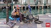 Musisi jalanan masih bisa dijumpai saat wisatawan berkeliling di kawasan Kota Sydney. Salah satunya seorang pria paruh baya yang memainkan gitar kecil dan harmonika di kawasan Circular Quay.