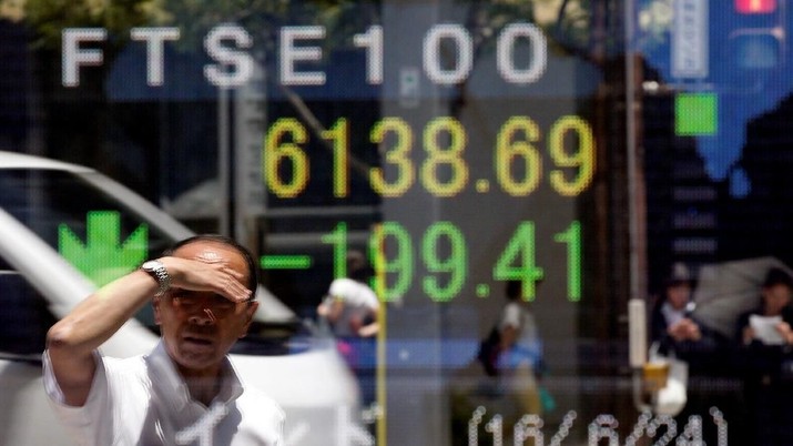 FILE PHOTO: A man is reflected in an electronic board showing Britain's FTSE 100 outside a brokerage in Tokyo, Japan, June 27, 2016.  REUTERS/Toru Hanai/File Photo