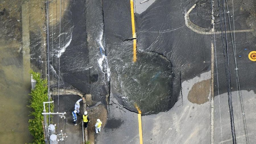 Water flows out from cracks in a road damaged by an earthquake in Takatsuki, Osaka prefecture, western Japan, in this photo taken by Kyodo June 18, 2018. Mandatory credit Kyodo/via REUTERS ATTENTION EDITORS - THIS IMAGE WAS PROVIDED BY A THIRD PARTY. MANDATORY CREDIT. JAPAN OUT. NO COMMERCIAL OR EDITORIAL SALES IN JAPAN.