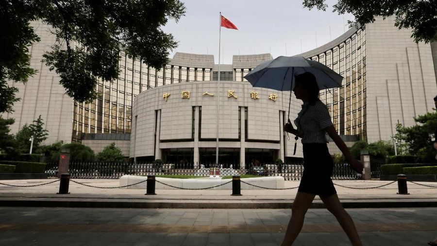 FILE PHOTO: A woman walks past the headquarters of the People's Bank of China (PBOC), the central bank, in Beijing, China June 21, 2013. REUTERS/Jason Lee/File Photo