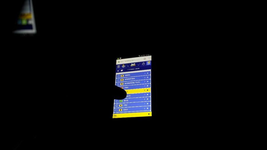 An online bet player holds a mobile phone as he bets at a betting house in Ladipo district, in Lagos, Nigeria, June 6, 2018. Picture taken June 6, 2018. REUTERS/Akintunde Akinleye