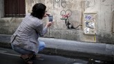 Salah satu karya ikonis Banksy adalah gambar tikus got yang duduk di bawah tulisan “Mei 1968” yang legendaris, mengenakan pita Minnie Mouse. Taman bermain Disneyland yang terletak di luar ibu kota Prancis menjadi salah satu perusahaan dengan pekerja terbanyak. (REUTERS/Benoit Tessier)