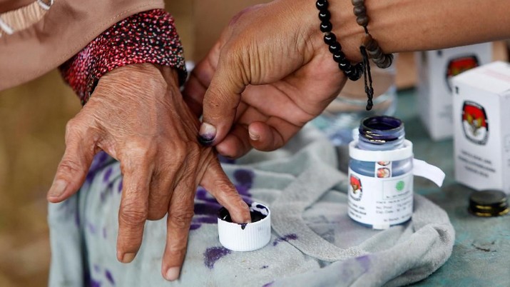 An election official helps an elderly woman to mark her finger with ink after casting her vote during regional elections in Tangerang, west of Jakarta, Indonesia June 27, 2018. REUTERS/Willy Kurniawan