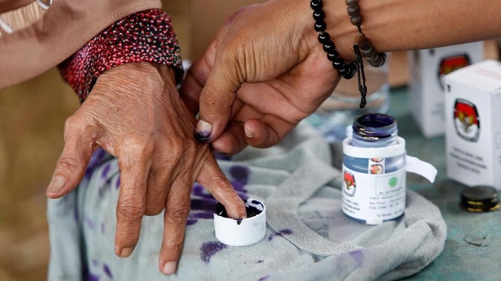 pilkada An election official helps an elderly woman to mark her finger with ink after casting her vote during regional elections in Tangerang, west of Jakarta, Indonesia June 27, 2018. REUTERS/Willy Kurniawan