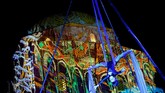 Seorang seniman tampil di depan masjid yang jadi 'layar' proyeksi festival the Zsolnay Light Festival, Hungaria, 28 Juni-1 Juli 2018. (REUTERS/Bernadett Szabo)