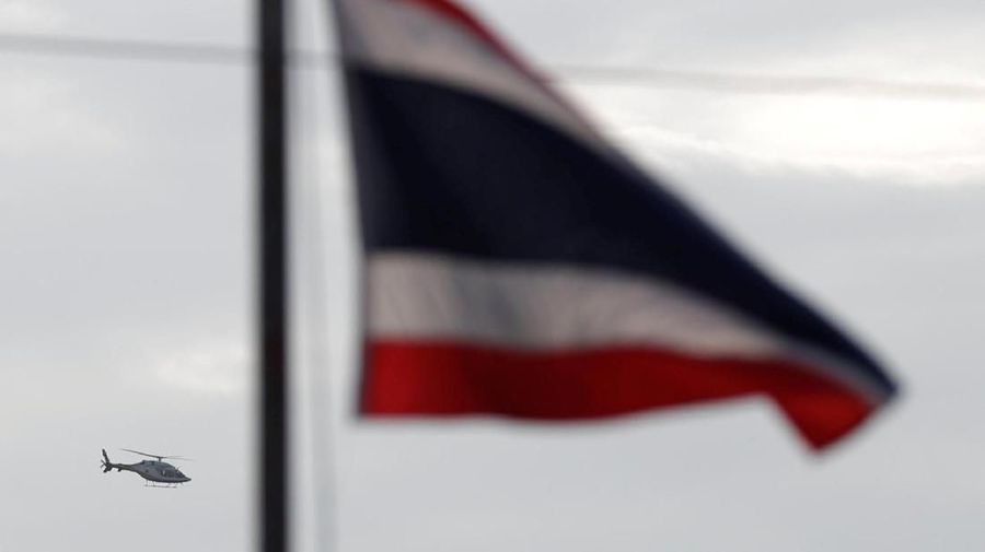 A helicopter carrying rescued schoolboys flies past a Thailand national flag in Chiang Rai, Thailand, July 9, 2018. REUTERS/Tyrone Siu