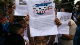 Para siswa menunjukkan karya mereka di depan Rumah Sakit Chiang Rai Prachanukroh, tempat 12 remaja dan pelatihnya dirawat selepas dari gua. (REUTERS/Athit Perawongmetha)