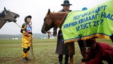 Seorang anak dan orangtuanya menyiapkan kuda untuk dipacu dalam Festival Naadam, di Ulaanbaatar, Mongolia. (REUTERS/B. Rentsendorj)