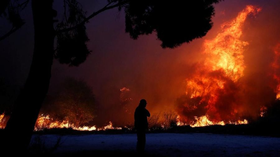 A man looks at the flames as a wildfire burns in the town of Rafina, near Athens, Greece, July 23, 2018. REUTERS/Costas Baltas      TPX IMAGES OF THE DAY