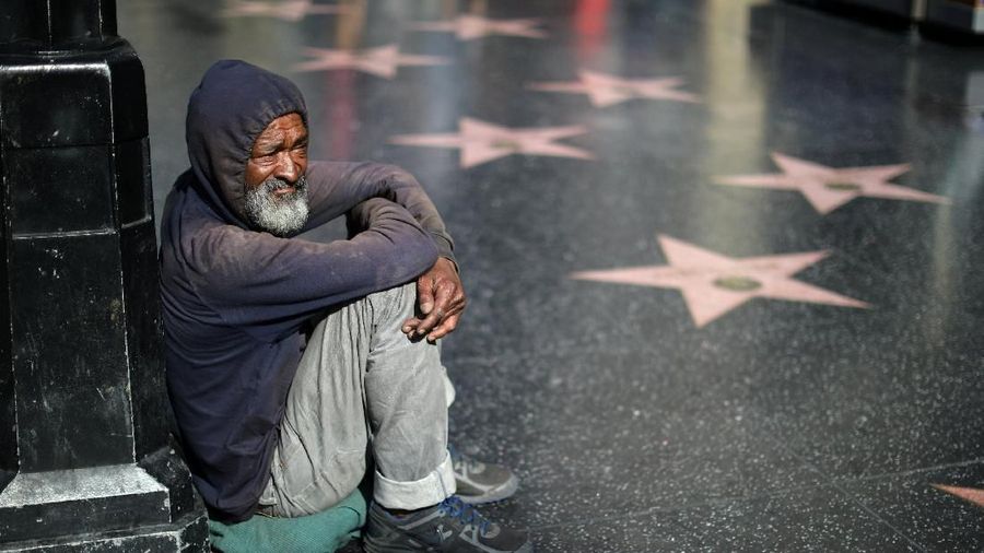 A homeless man watches people viewing President Donald Trump's vandalized star on the Hollywood Walk of Fame in Hollywood, Los Angeles, California, U.S. July 25, 2018. REUTERS/Lucy Nicholson