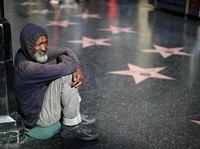 A homeless man watches people viewing President Donald Trump's vandalized star on the Hollywood Walk of Fame in Hollywood, Los Angeles, California, U.S. July 25, 2018. REUTERS/Lucy Nicholson