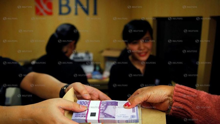 FILE PHOTO: A woman holds Indonesian rupiah banknotes at a Bank Negara Indonesia (BNI) mobile bank in Jakarta July 15, 2013. REUTERS/Beawiharta/File Photo