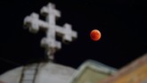 Dari sebuah Gereja Ortodoks Koptik di Amman, Yordania, gerhana bulan terlihat berwarna kemerahan. Mars akan terlihat terang dan hujan meteor juga terjadi bersamaan dengan gerhana bulan. (Reuters/Muhammad Hamed)