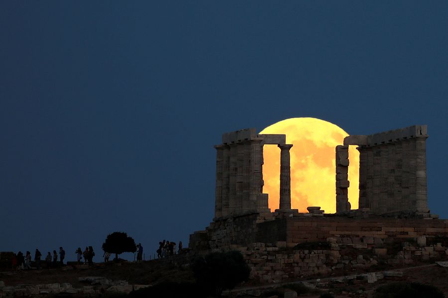 People watch a full moon rising behind the Temple of Poseidon before a lunar eclipse in Cape Sounion, near Athens, Greece, July 27, 2018. REUTERS/Alkis Konstantinidis      TPX IMAGES OF THE DAY
