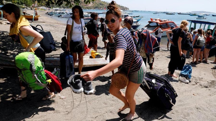 Orang-orang berkerumun di pantai saat mereka berusaha meninggalkan Kepulauan Gili.