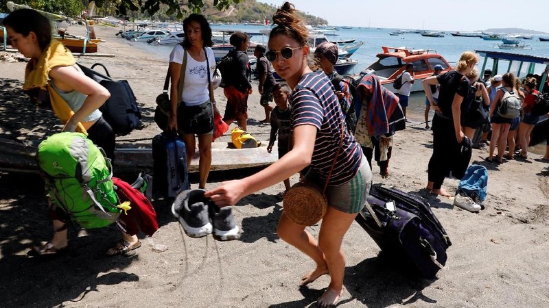 Orang-orang berkerumun di pantai saat mereka berusaha meninggalkan Kepulauan Gili.
