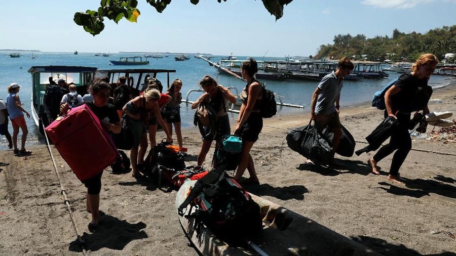 Orang-orang berkerumun di pantai saat mereka berusaha meninggalkan Kepulauan Gili.