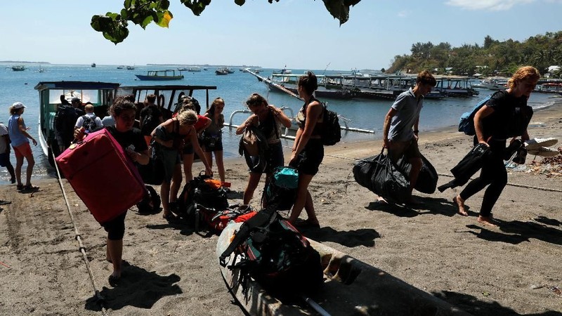 Orang-orang berkerumun di pantai saat mereka berusaha meninggalkan Kepulauan Gili.