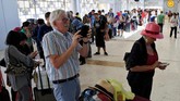 Turis asing memerhatikan ponsel saat menunggu dapat masuk ke dalam bandara internasional Lombok, Senin (6/8). (REUTERS/Beawiharta)