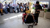 Seorang anak yang kelelahan beristirahat di atas koper yang ditumpuk di troli. Kepanikan, terutama di kalangan turis, terjadi setelah gempa berkekuatan 7 SR yang mengguncangkan kepulauan Lombok, NTB. (REUTERS/Beawiharta)