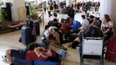 Rombongan turis asing beristirahat di lantai bandara internasional Lombok menunggu mendapatkan penerbangan yang akan membawa mereka terbang dari salah satu destinasi favorit pariwisata Indonesia. (REUTERS/Beawiharta)