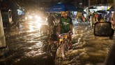 Seorang pria coba untuk menarik becak pada suatu jalanan yang banjir di kota Yangon. Hujan deras telah membuat daerah Mekong terkena dampak dengan Myanmar yang dilanda banjir parah yang memaksa 150 ribu orang mengungsi. (AFP PHOTO / YE AUNG THU)