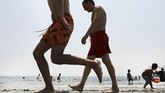 Pada musim panas, orang-orang berjalan di suatu pantai di Pulau Coney di New York. Saat itu New York mengalami gelombang panas sehingga penduduk kota berbondong-bondong mendatangi kolam renang dan pantai untuk mendinginkan badan. (Spencer Platt/Getty Images/AFP)