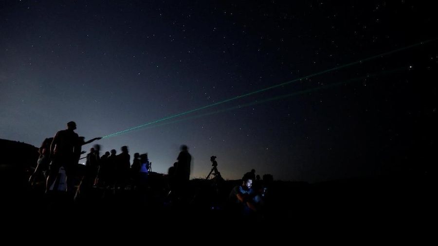 A man points a laser into the sky as people watch the Perseid meteor shower at Dwejra, outside the village of San Lawrenz on the island of Gozo, Malta August 12, 2018. REUTERS/Darrin Zammit Lupi