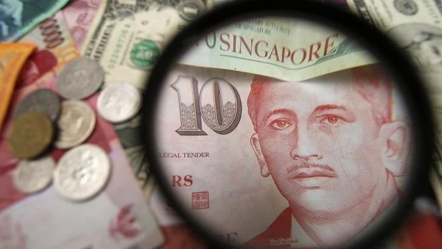 Singapore currency notes are seen through a magnifying glass among other currencies in this photo illustration taken in Singapore April 12, 2013. REUTERS/Edgar Su