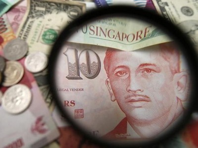 Singapore currency notes are seen through a magnifying glass among other currencies in this photo illustration taken in Singapore April 12, 2013. REUTERS/Edgar Su