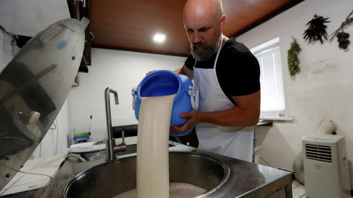 Alexey Dubovets pours milk during cheese making at his family dairy and cheese farm in the Siberian village of Sizaya, south of Krasnoyarsk, Russia August 8, 2018. Picture taken August 8, 2018. REUTERS/Ilya Naymushin