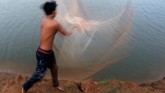 Seorang pria menebar jaring pada suatu danau di luar kota Phnom Penh, Kamboja. (REUTERS/Samrang Pring)