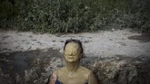 Seorang perempuan yang tubuhnya tertutupi lumpur menikmati sinar matahari di Ovca, dekat Beograd, untuk mendinginkan badan dari sengat gelombang panas. (AFP PHOTO / OLIVER BUNIC)