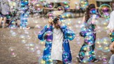 Seorang wisatawan mengambil foto gelembung-gelembung udara yang diciptakan oleh seorang seniman jalanan di Frankfurt, Jerman. (AFP PHOTO / dpa / Frank Rumpenhorst)