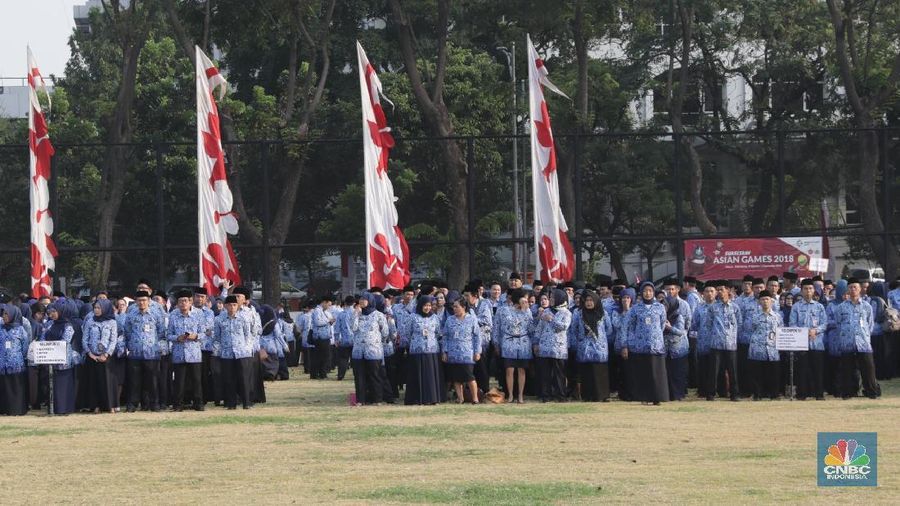 Pegawai PNS tiba menghadiri Upacara Kemerdekaan RI ke-73 di Lapangan Banteng, Jakarta, Jumat (17/8). Upacara diikuti pejabat Pemerintah Provinsi DKI Jakarta dan ratusan pegawai negeri sipil (PNS) DKI Jakarta yang berbaris memanjang dengan mengenakan batik Korpri biru dan celana hitam. Bagi peserta upacara pria mengenakan peci hitam. Tak ketinggalan pelajar, petugas pemadam kebakaran, anggota Kepolisian RI (Polri), Tentara Nasional Indonesia (TNI) baik itu angkatan darat, laut, dan udara ikut dalam barisan upacara.(CNBC Indonesia/Muhammad Sabki)