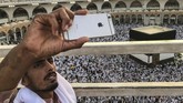 Seorang jemaah calon haji tengah berswafoto dengan latar jemaah calon haji lainnya tengah melingkari Kakbah dan berdoa di Masjid Agung, Mekah, Arab Saudi, Kamis (16/8). (REUTERS/Zohra Bensemra).