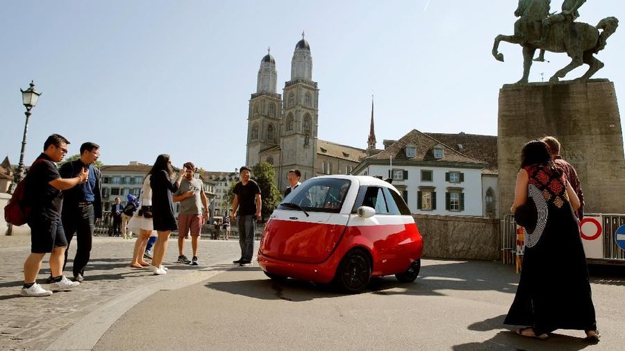 People take pictures of an electric-powered Microlino car of Swiss Microlino AG parked in front of the Grossmuenster church in Zurich, Switzerland August 16, 2018. REUTERS/Arnd Wiegmann