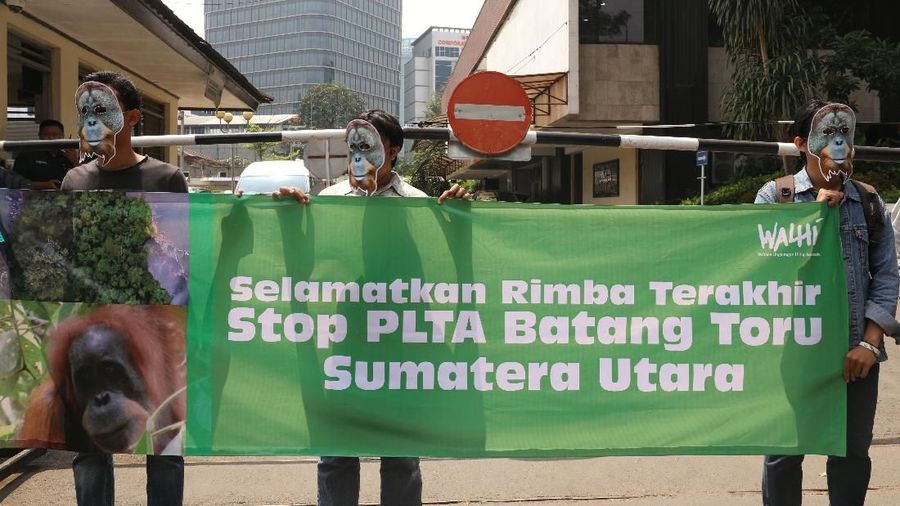 Belasan orang memegangi poster, yang bertuliskan segera mencabut dan menghentikan sementara pembangunan Pembangkit Listrik Tenaga Air (PLTA) di Batang Toru.