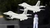 Dua miniatur jet F-16 yang ditempel di kaca terlihat seolah terbang melewati seorang pengunjung Museum Angkatan Udara di Arlington, Virgia, AS. (Reuters/Kevin Lamarque)