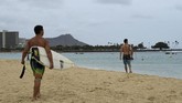 Sementara itu, para peselancar justru memanfaatkan ombak tenang mungkin untuk yang terakhir kalinya sebelum badai menerjang. (Reuters/Hugh Gentry)