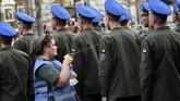 Seorang perawat militer menyemprotkan air untuk mendinginkan tubuh para tentara saat digelarnya latihan pawai Hari Kemerdekaan Ukraina di pusat kota Kiev. (AFP/Sergei Supinsky)