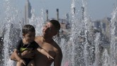 Seorang ayah mengajak anaknya bermain air mancur untuk menghalau udara gerah di Taman Domino, Brooklyn, New York. (REUTERS/Andrew Kelly)
