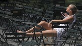 Seorang wanita terlihat bersantai di Taman Bryant Park, Manhattan, New York. (REUTERS/Andrew Kelly)