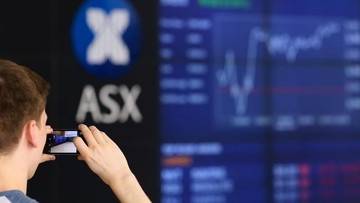 FILE PHOTO: A visitor takes a photograph of a board displaying stock prices at the Australian Securities Exchange (ASX) in Sydney, Australia March 6, 2017. REUTERS/Steven Saphore