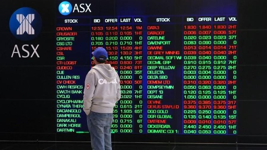 FILE PHOTO - An investor looks at a board displaying stock prices at the Australian Securities Exchange (ASX) in Sydney, Australia, July 17, 2017. REUTERS/Steven Saphore