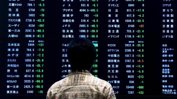 A woman stands in front of a display showing market indices at the Tokyo Stock Exchange (TSE) in Tokyo June 29, 2015. REUTERS/Thomas Peter