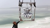 Seniman asal Israel Sigalit Landau tengah menahan kotak besi yang menyimpan karyanya, sebuah tutu yang terbungkus dengan garam dari Laut Mati. (REUTERS/Nir Elias)