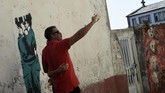 Bahkan, seniman mural legendaris Bansky disebut sempat memberikan kontribusi dalam dinding di kawasan ini. Namun Bansky membantah bahwa karya penjaga berciuman seperti di gambar ini adalah miliknya. (AFP PHOTO / MIGUEL RIOPA)