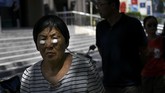 Seorang wanita dengan bola-bola kapas menempel di wajahnya berjalan di kota Beijing. (AFP PHOTO / WANG ZHAO)